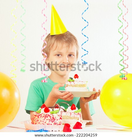 Little kid in holiday hat with a piece of birthday cake and balloons