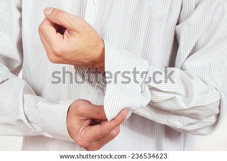 Man unbuttons his sleeve bright shirt close up
