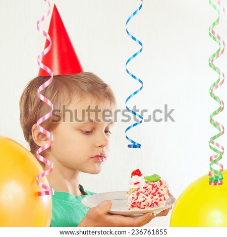 Little child in holiday hat eating a birthday cake