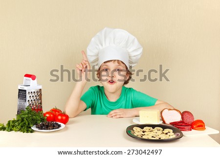 Little funny chef at the table with ingredients for pizza