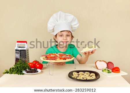 Little boy in chefs hat with a grated cheese for pizza