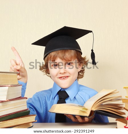 Little smiling boy in academic hat quoted the old book