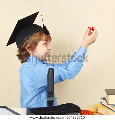 Little professor in academic hat conducts research with the microscope