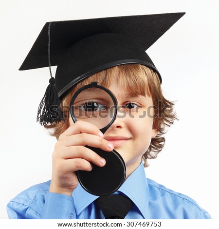 Little boy in academic hat with a magnifying glass on a white background