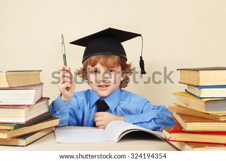 Little boy in academic hat with rarity pen among the old books