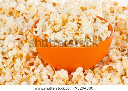Popcorn in a orange bowl on a background of popcorn