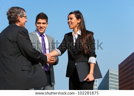 Young business couple shaking hands with partner outdoors.