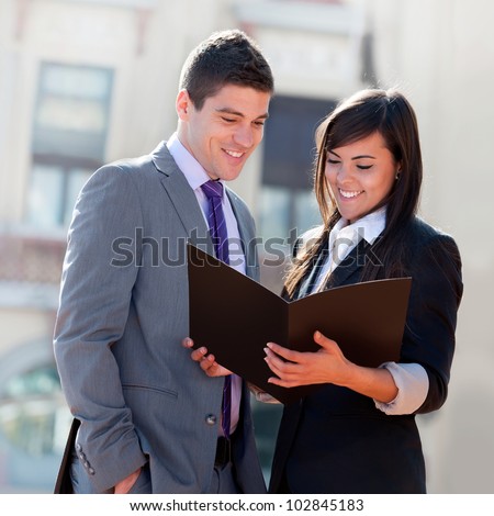 Young Business couple looking at file outdoors.
