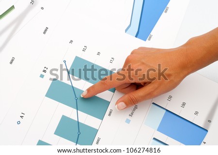 Close up of female hand pointing on business graphics.