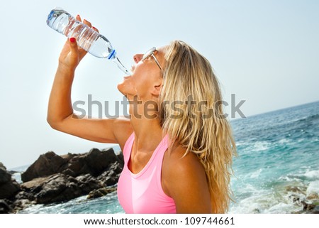 Close up portrait of Woman drinking water after fitness workout outdoors.