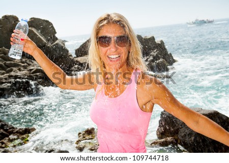 Close up portrait of attractive woman splashing water after jogging outdoors.