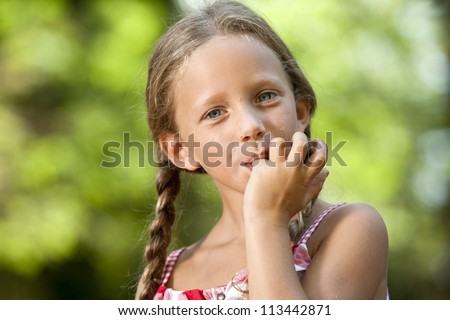 Portrait of cute girl licking off chocolate fingers outdoors.