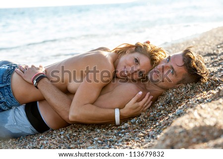 Handsome romantic couple embracing on pebble beach.
