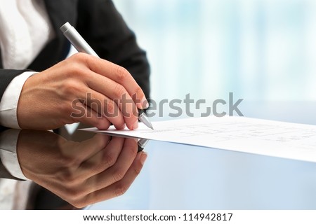 Extreme close up of female business hand signing document.