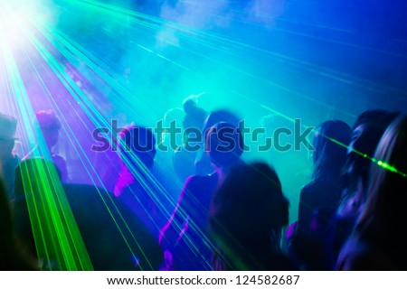 Crowd of people dancing under disco laser light.
