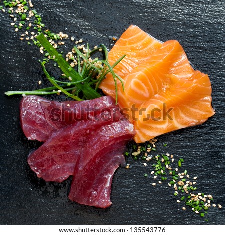 Close up of fresh tuna and salmon sashimi on black plate.