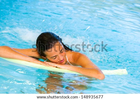 Attractive young woman relaxing under cascade in spa pool.