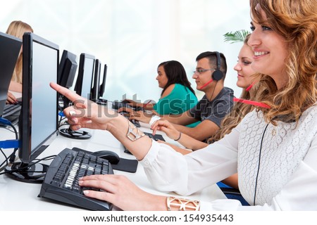 Close up portrait of young female student pointing at blank computer screen in office.