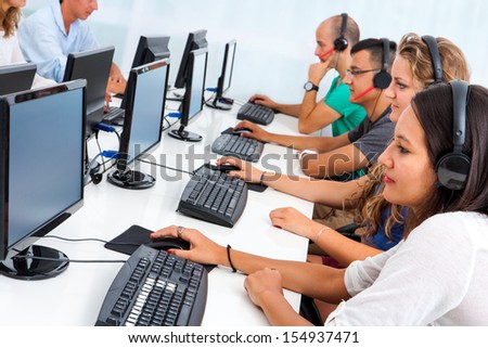 Group of young business students working together on computers in office.