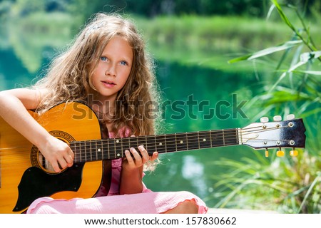 Close up portrait of young guitar student playing spanish guitar at lake.