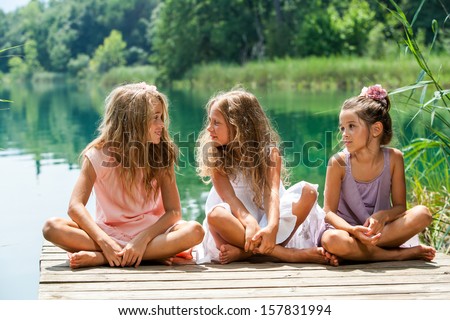 Portrait Of Young Female Threesome Having Conversation On River Jetty.