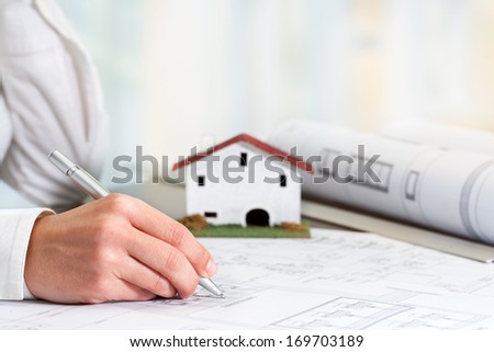 Close up of female hand working on real estate business documents.