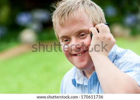 Close up portrait of handicapped boy talking on smart phone outdoors.