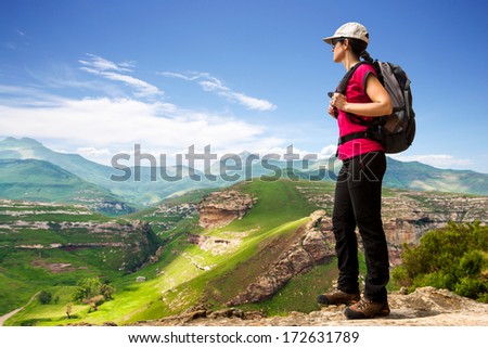 Young female hiking tourist on cliff contemplating open view.
