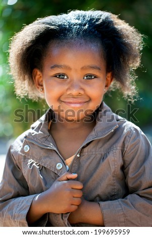 Outdoor portrait of cute African girl wearing brown jacket.