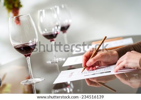 Close up of female hands writing notes at wine tasting.