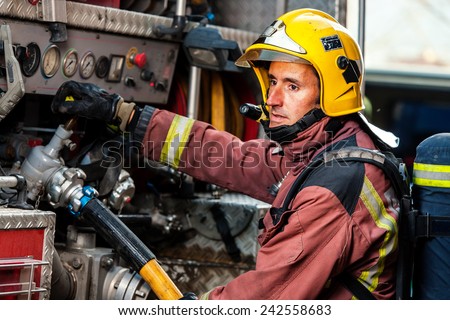 Fireman controlling water pressure at back of fire truck.