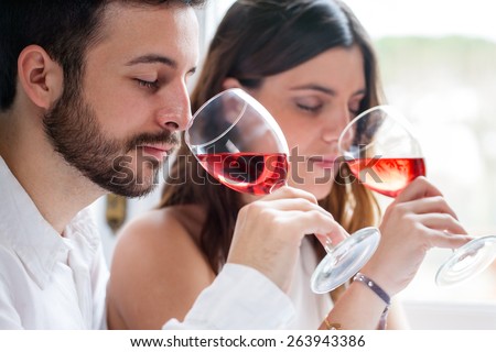 Close up portrait of young couple at wine tasting. Man and woman smelling wine with eyes closed.