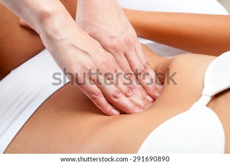 Macro close up of therapist hands doing visceral massage on female abdomen.