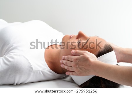 Close up of practitioner doing reiki with hands on young woman. Therapist doing healing treatment with hands next to head.