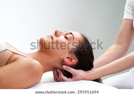 Close up of  chiropractor pressing back of head. Therapist doing healing massage with fingers at back of neck.