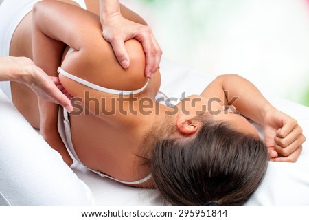 Close up top view of osteopath doing healing treatment on female shoulder blade.