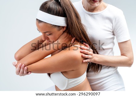Close up of physiotherapist doing shoulder rotation massage on young woman.