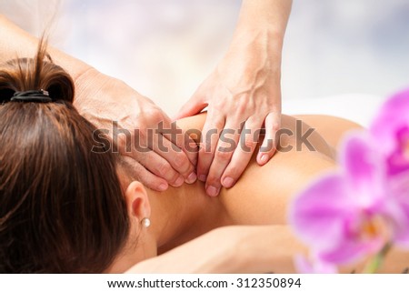 Macro close up of hands massaging female neck and shoulders.