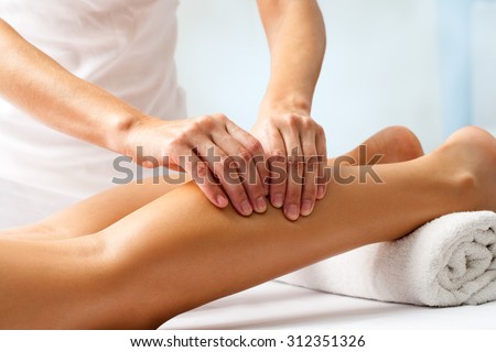 Detail of hands massaging human calf muscle.Therapist applying pressure on female leg.