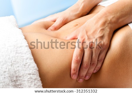 Macro close up of hands massaging female abdomen.Therapist applying pressure on belly.