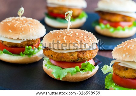 Extreme close up of multiple Appetizing mini chicken burgers. Small burgers in row for catering service.