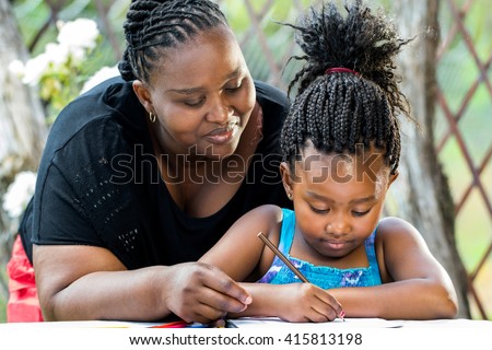 Close up portrait of african teacher supervising little kid doing homework outdoors.