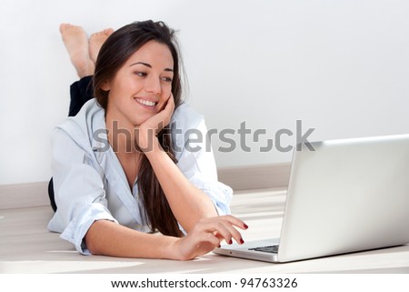 Young attractive woman laying on floor while working with laptop.