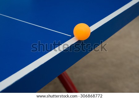 pingpong ball hits the edge of a blue pingpong table