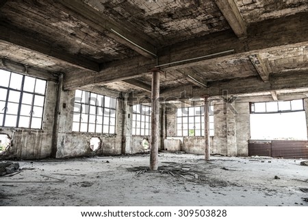 Empty industrial loft in an architectural background with bare cement walls, floors and pillars supporting a mezzanine