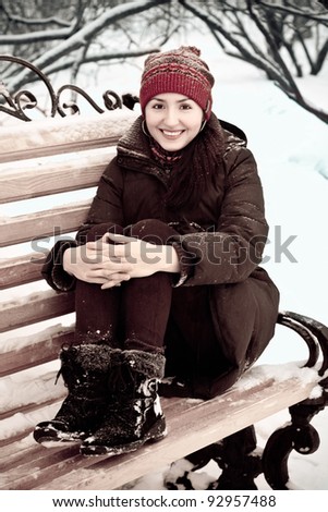 young woman in a red cap in winter park on a bench