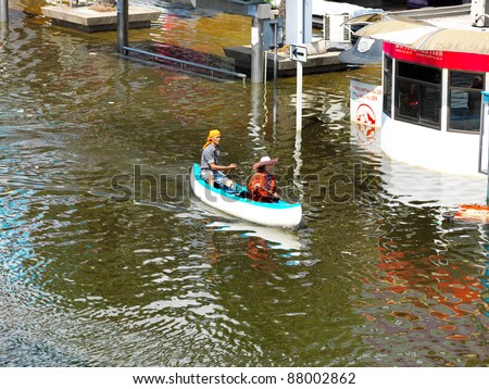 PHATHUMTRANI, THAILAND- OCTOBER 21: couple use boat as a transportation through water during the worst flooding in decades on October 21, 2011 Rongsit Road, Phathumtrani, Thailand.
