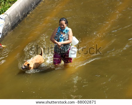 PHATHUMTRANI, THAILAND- OCTOBER 21: Elderly woman goes to get food and drink, walks through water during the worst flooding in decades on October 21, 2011 Rongsit Road, Phathumtrani, Thailand.