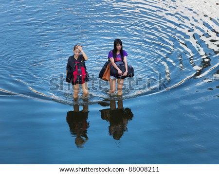 PHATHUMTRANI, THAILAND- OCTOBER 21: women walk on main road during the worst flooding disaster in decades on October 21, 2011 Rongsit Road, Phathumtrani, Thailand.