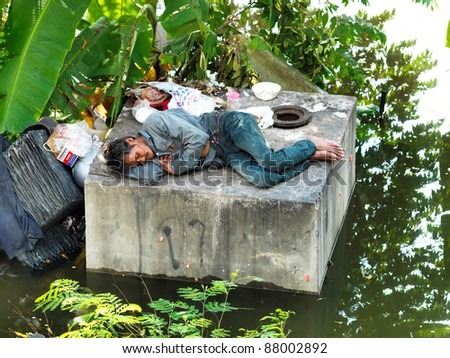 PHATHUMTRANI, THAILAND- OCTOBER 21: Flood victim becomes homeless, sleeps above the concrete, during the worst flooding in decades on October 21, 2011 Rongsit Road, Phathumtrani, Thailand.